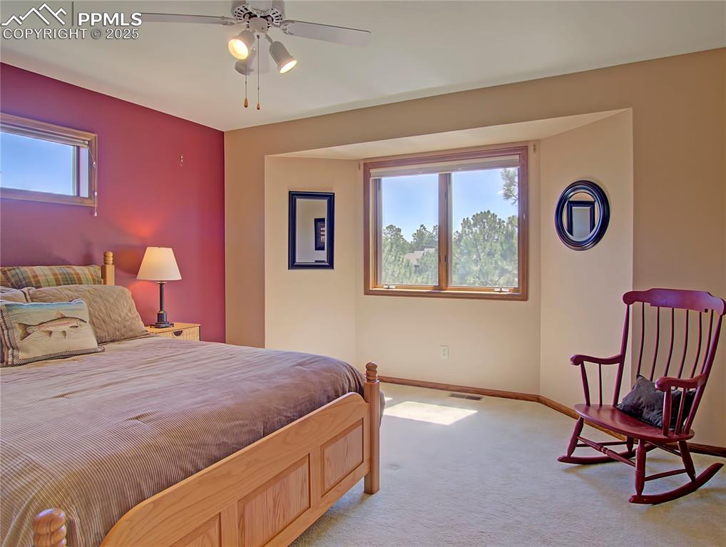 Image 28 of 40: Upstairs bedroom with bay window, blinds, & ceiling fan.