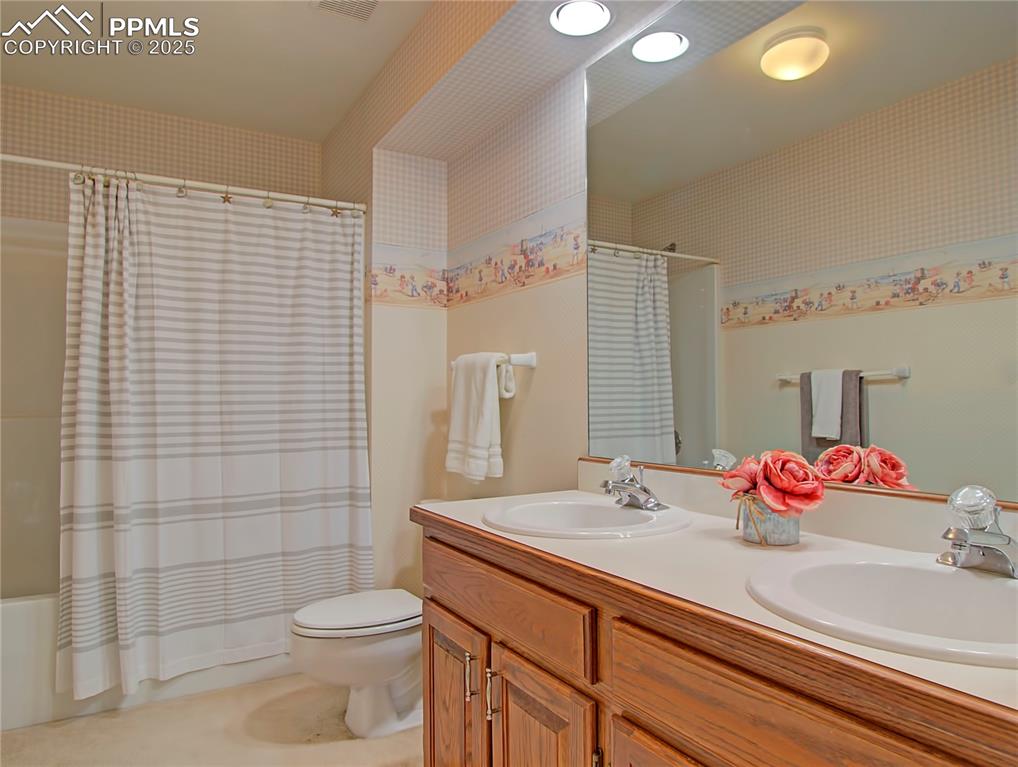 Image 30 of 40: Upstairs hall full bathroom with two sinks provides space for siblings.