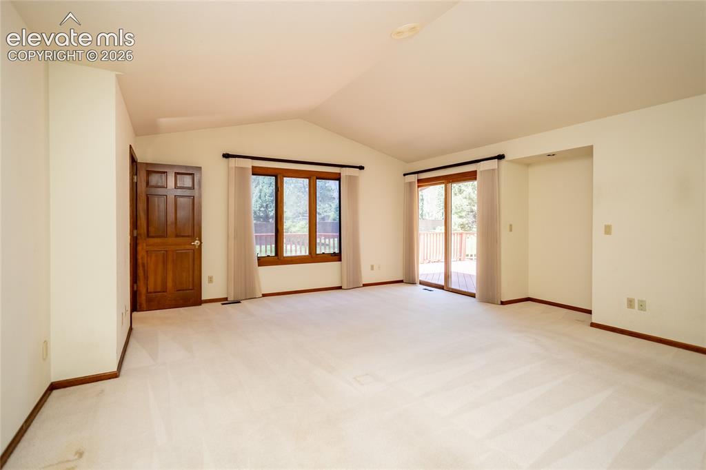 Image 13 of 40: Spacious room featuring vaulted ceilings, light-toned carpeting, and a rich