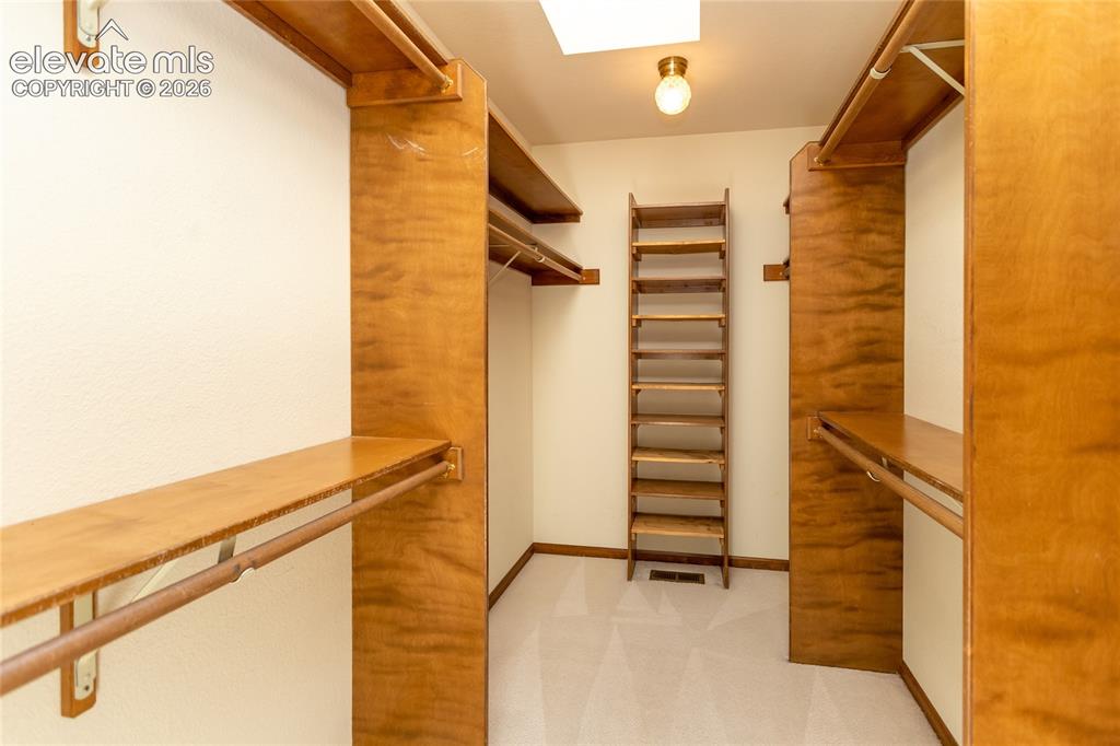 Image 15 of 40: Walk-in closet featuring extensive built-in wooden shelving, multiple hangi