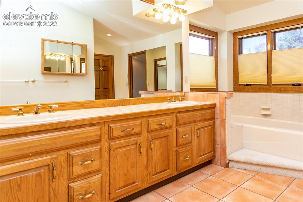 Image 18 of 40: Bathroom featuring a double vanity with light wood cabinetry, dual sinks, a