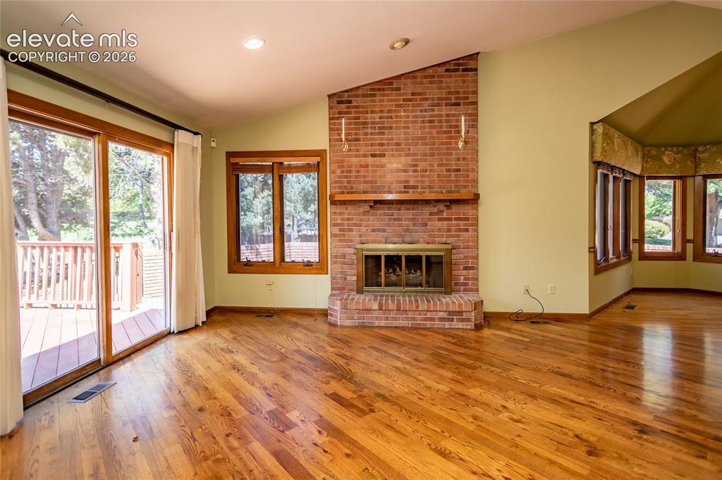 Image 19 of 40: Living area featuring wood-finish flooring, a brick fireplace with a wood m
