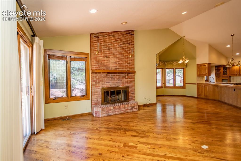 Image 20 of 40: Spacious room featuring wood-finish flooring, a brick fireplace with a hear