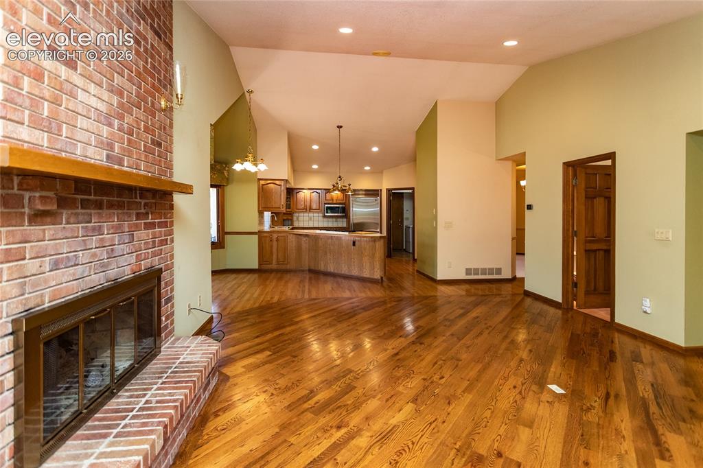 Image 21 of 40: Brick fireplace with a wood mantel, wood-finish flooring, vaulted ceiling, 