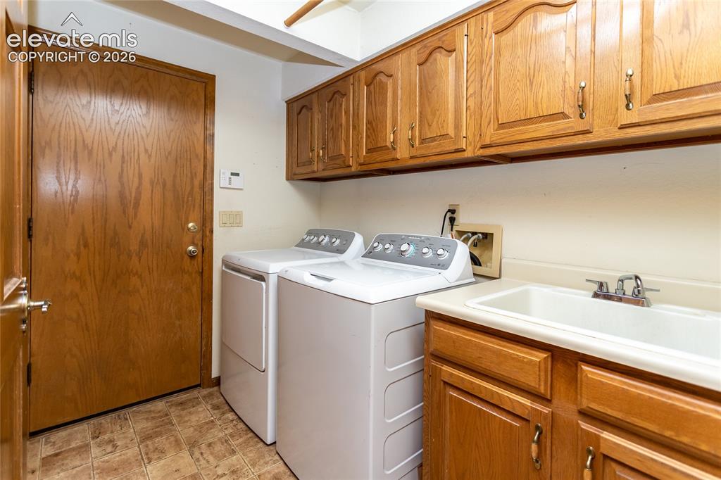 Image 22 of 40: Dedicated laundry area featuring durable flooring, wood-finish cabinetry, a