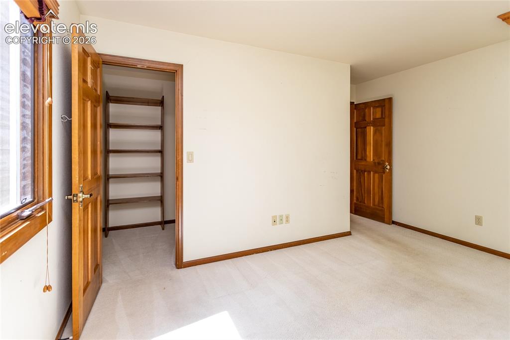 Image 23 of 40: Carpeted room with light-toned walls and natural wood trim