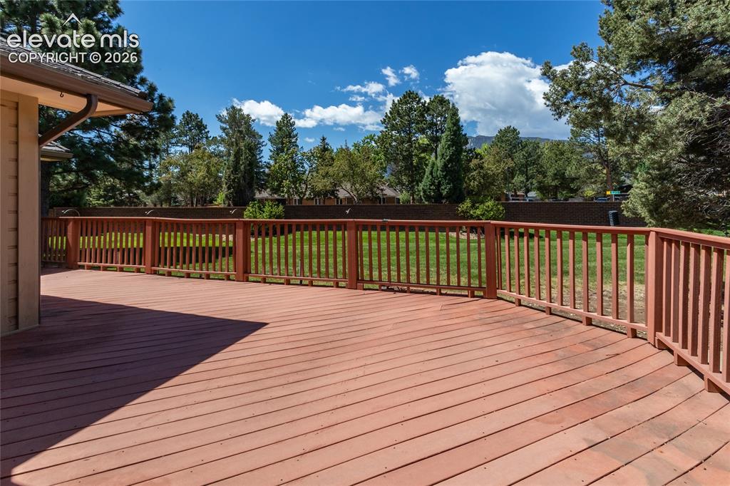 Image 28 of 40: Expansive outdoor deck with red-toned wood flooring and matching railings