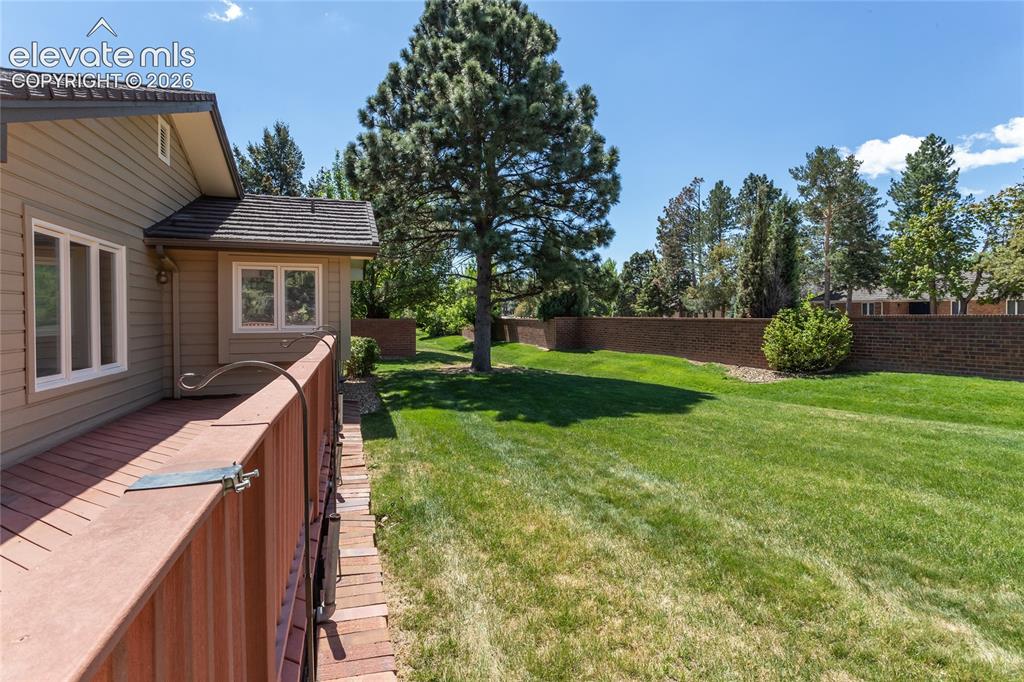 Image 30 of 40: Expansive green lawn with mature trees and a substantial brick retaining wa