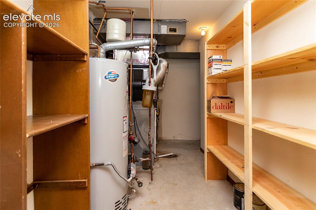 Image 31 of 40: Utility room featuring a water heater, copper piping, and dual built-in she