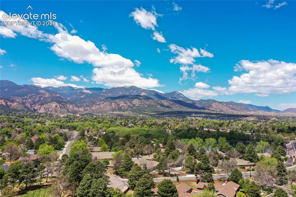 Image 35 of 40: Expansive mountain scenery framing a residential landscape with mature tree