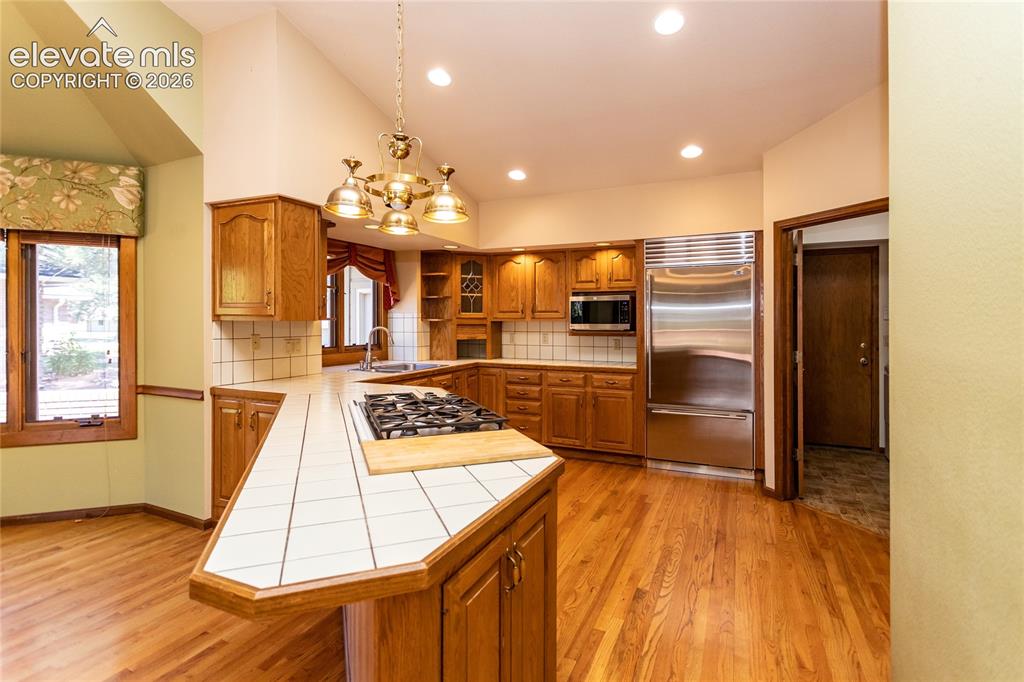 Image 6 of 40: Kitchen featuring a central island with a built-in cooktop, tile countertop