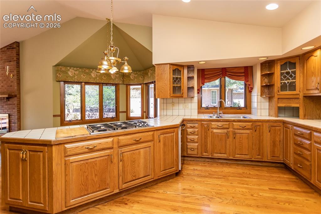 Image 7 of 40: Kitchen featuring natural wood cabinetry, tile countertops, a built-in gas 