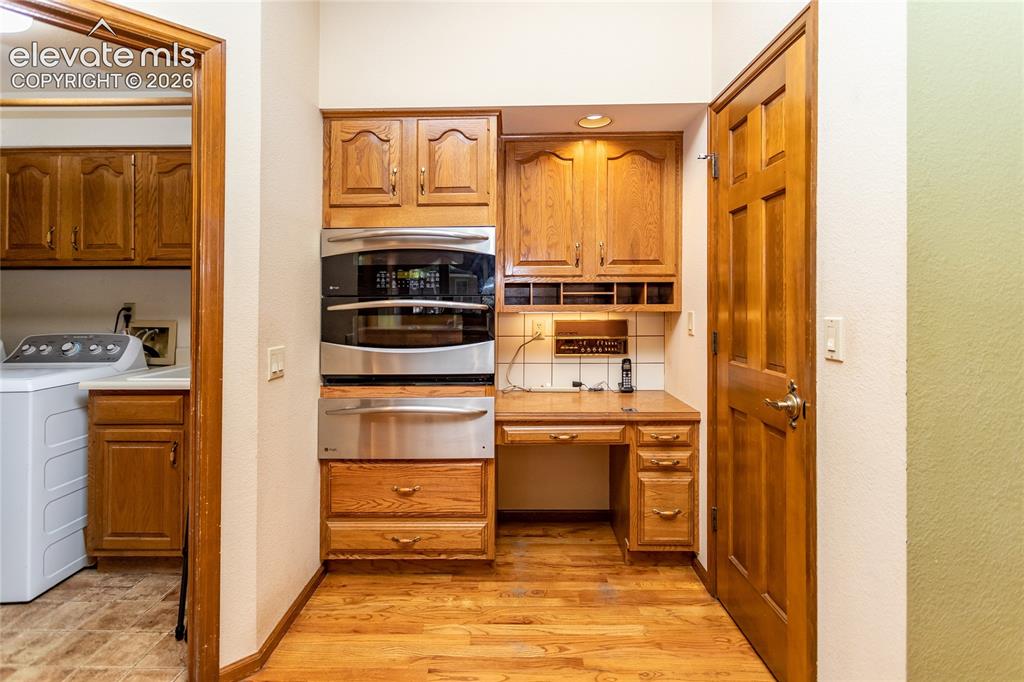 Image 8 of 40: Built-in double ovens and a warming drawer are complemented by wood cabinet