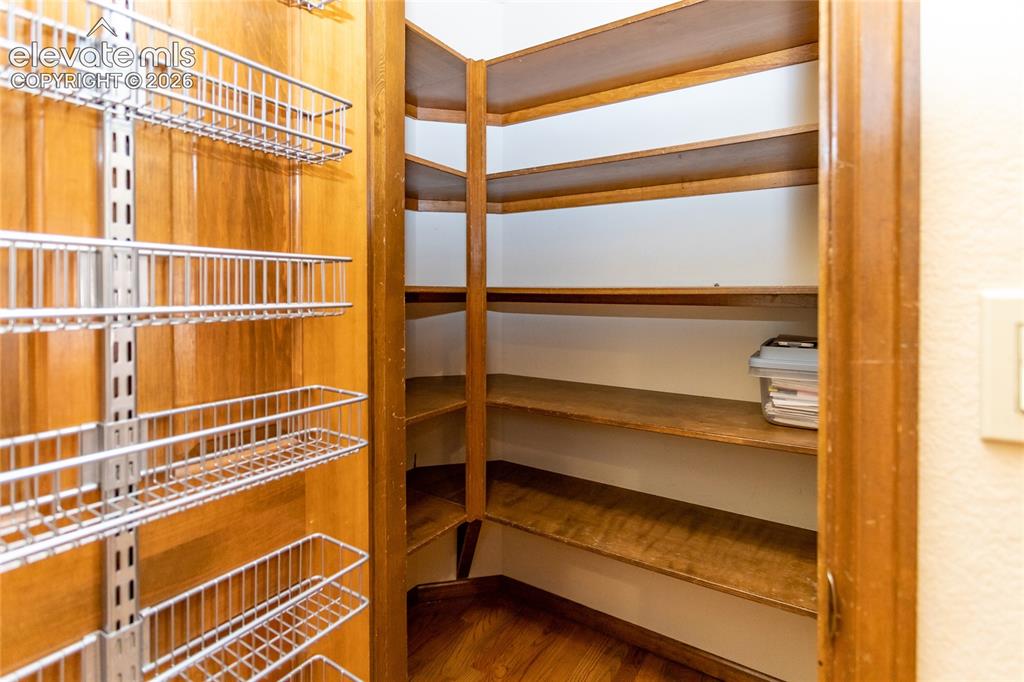 Image 9 of 40: Walk-in pantry with wood-finish flooring, built-in shelving, and adjustable