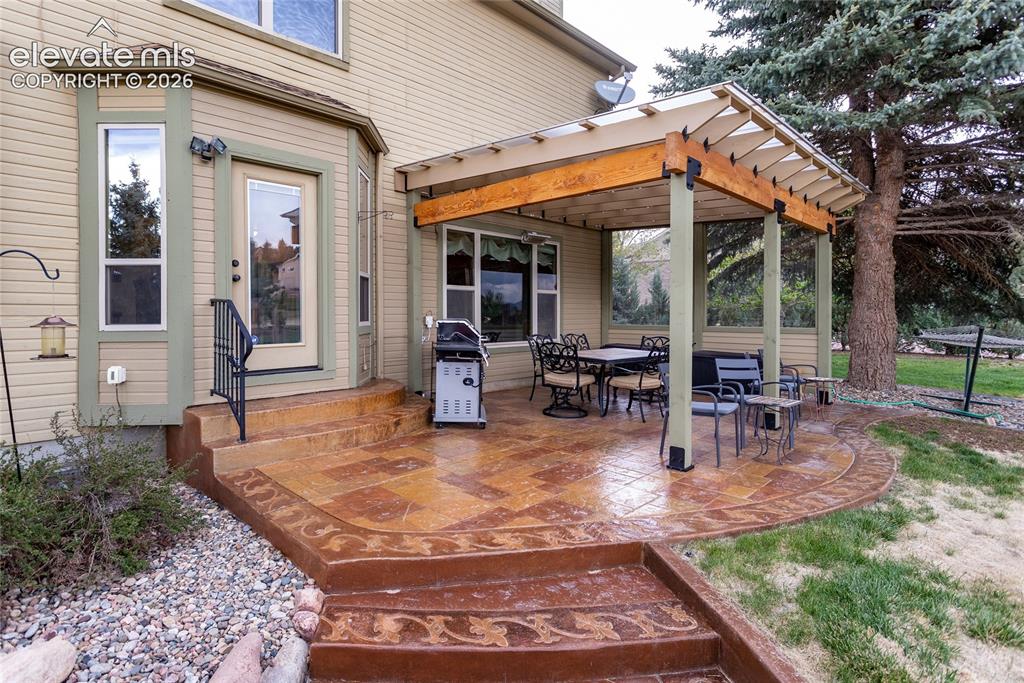 Image 41 of 50: Beautiful Stamped Concrete and Covered Patio overlooks the Yard and Open Sp