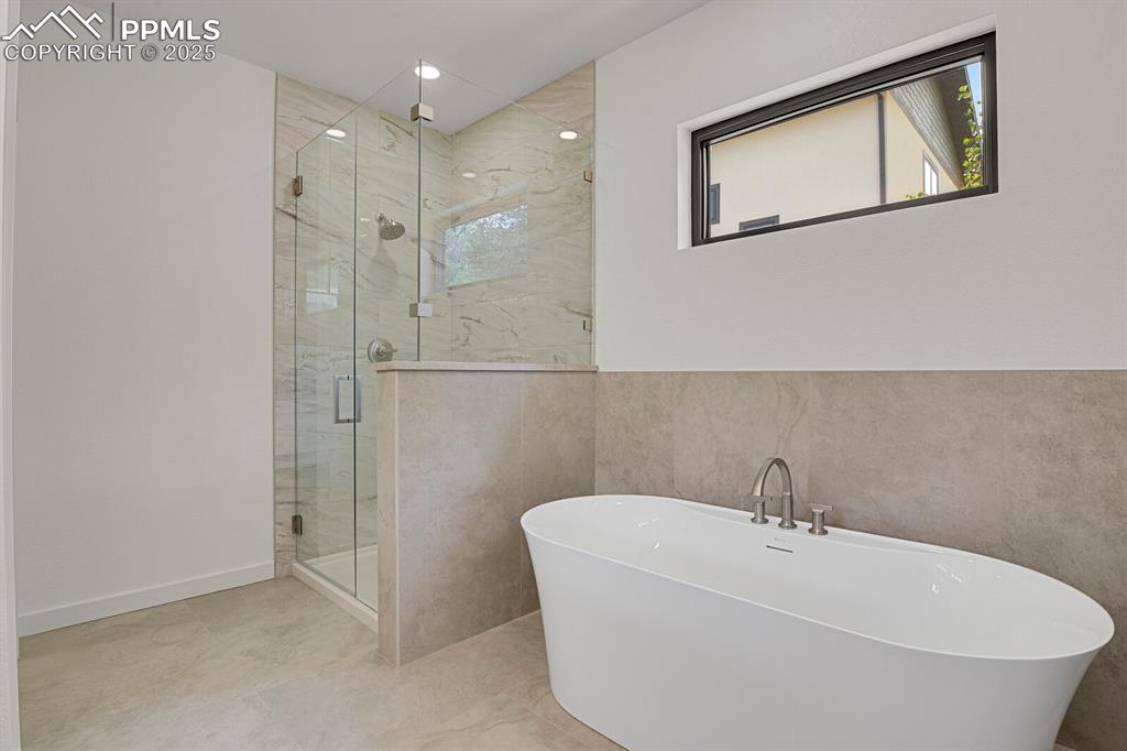 Image 12 of 49: Spa inspired primary bathroom with frameless glass shower and soaking tub