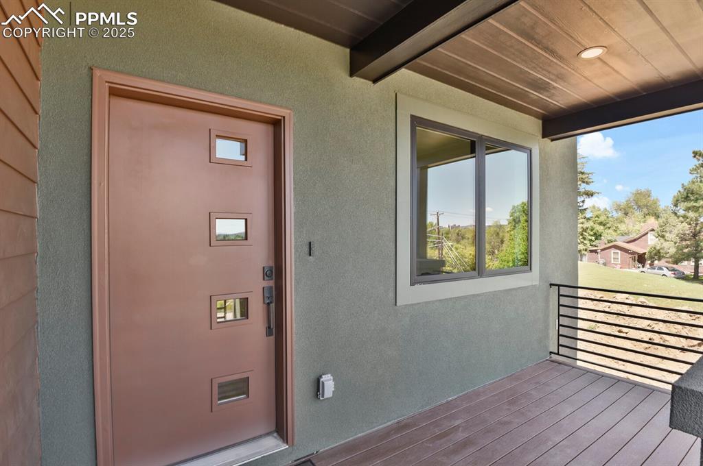 Image 4 of 49: Welcoming front porch with custom fabricated metal railing and Trex Transce
