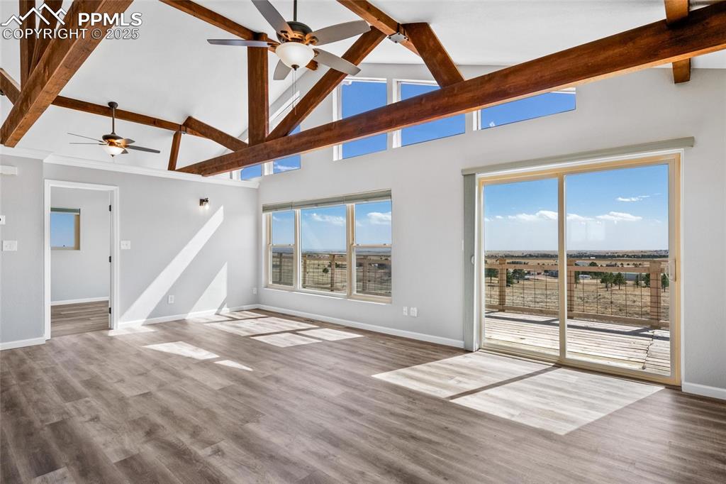 Image 10 of 38: Unfurnished living room featuring a ceiling fan, beamed ceiling, baseboards