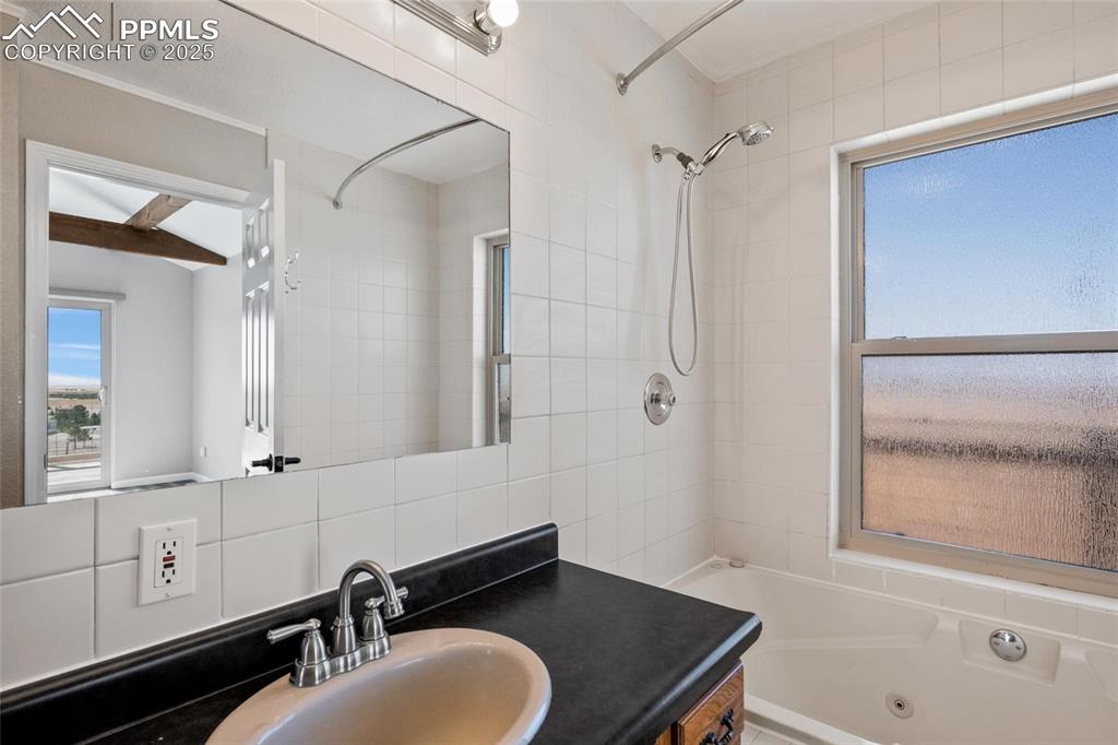 Image 16 of 38: Bathroom featuring a combined bath / shower with jetted tub, vanity, and de