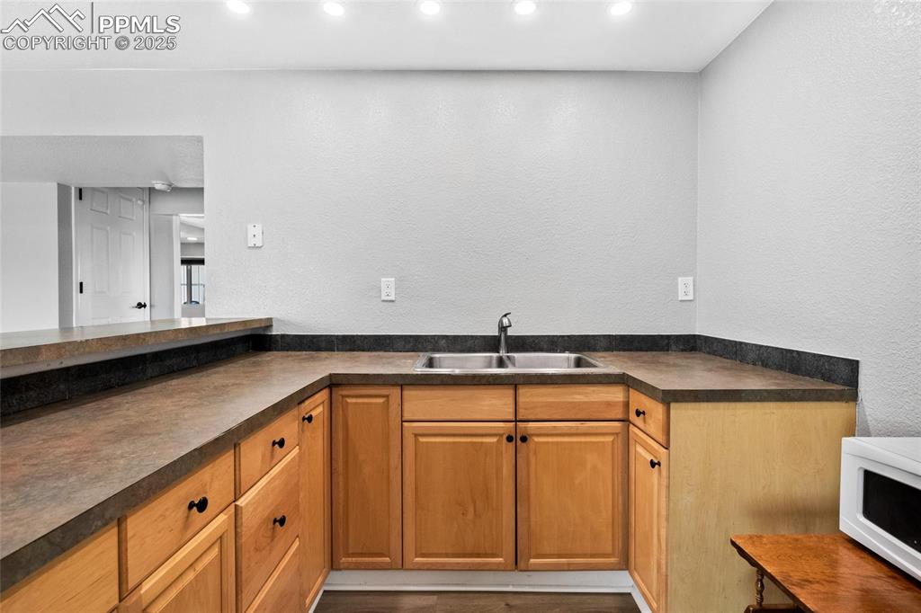 Image 21 of 38: Kitchen featuring a sink, dark countertops, white microwave, recessed light