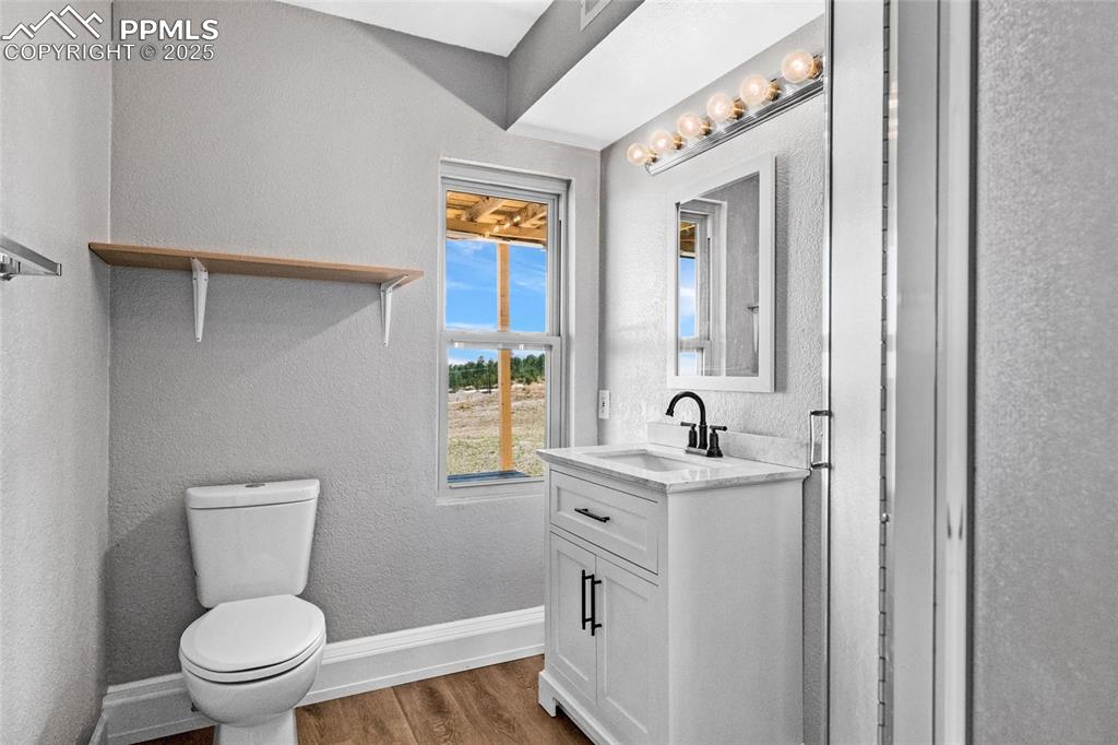 Image 26 of 38: Bathroom with vanity, toilet, wood finished floors, baseboards, and a textu