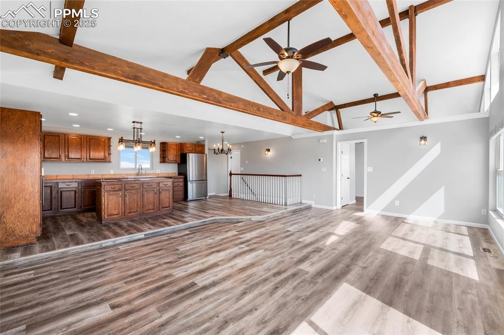Image 3 of 38: Unfurnished living room with a sink, a chandelier, ceiling fan, high vaulte