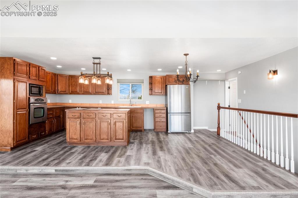 Image 4 of 38: Kitchen with stainless steel appliances, a chandelier, a sink, light wood-s