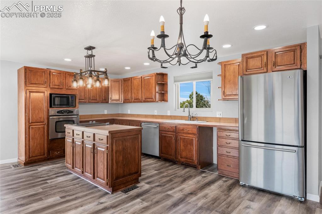 Image 7 of 38: Kitchen with stainless steel appliances, a chandelier, dark wood finished f