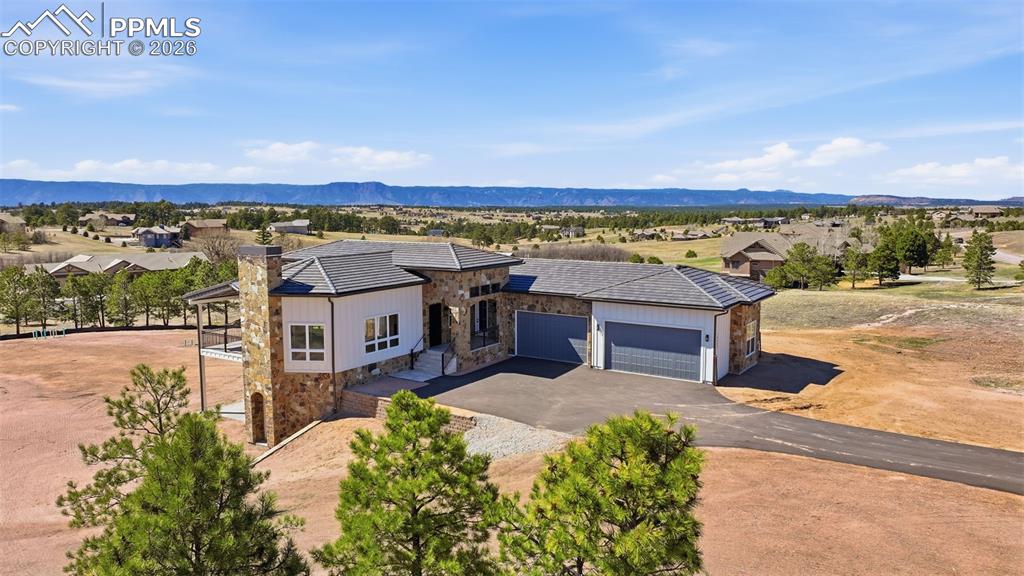 Image 1 of 45: View from front of home with stone siding, a garage, driveway, a mountain v