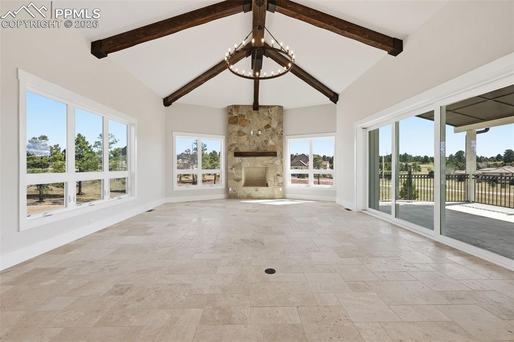 Image 12 of 45: Unfurnished living room with stone tile flooring, a stone fireplace, hangin