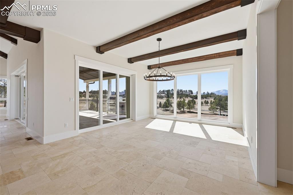 Image 13 of 45: Dining Room with suspended lighting, beamed ceiling, stone tile flooring, a