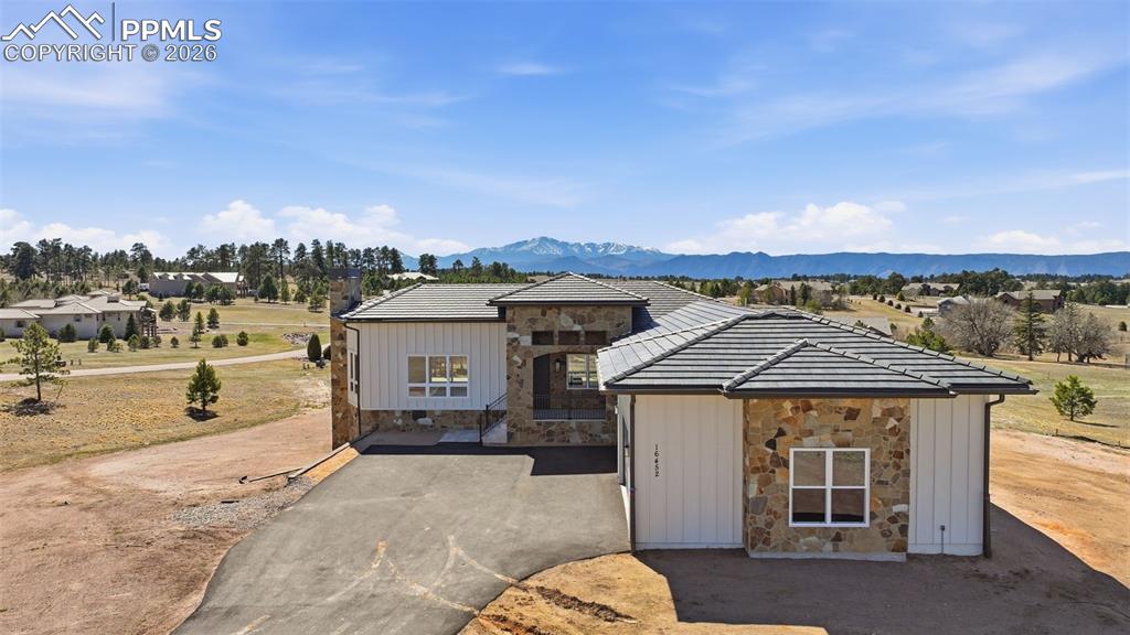 Image 2 of 45: Modern farmhouse featuring stone siding, asphalt driveway, a mountain view,