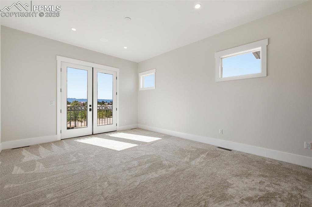 Image 21 of 45: Master Bedroom Suite with French doors, light carpet, natural light, and re