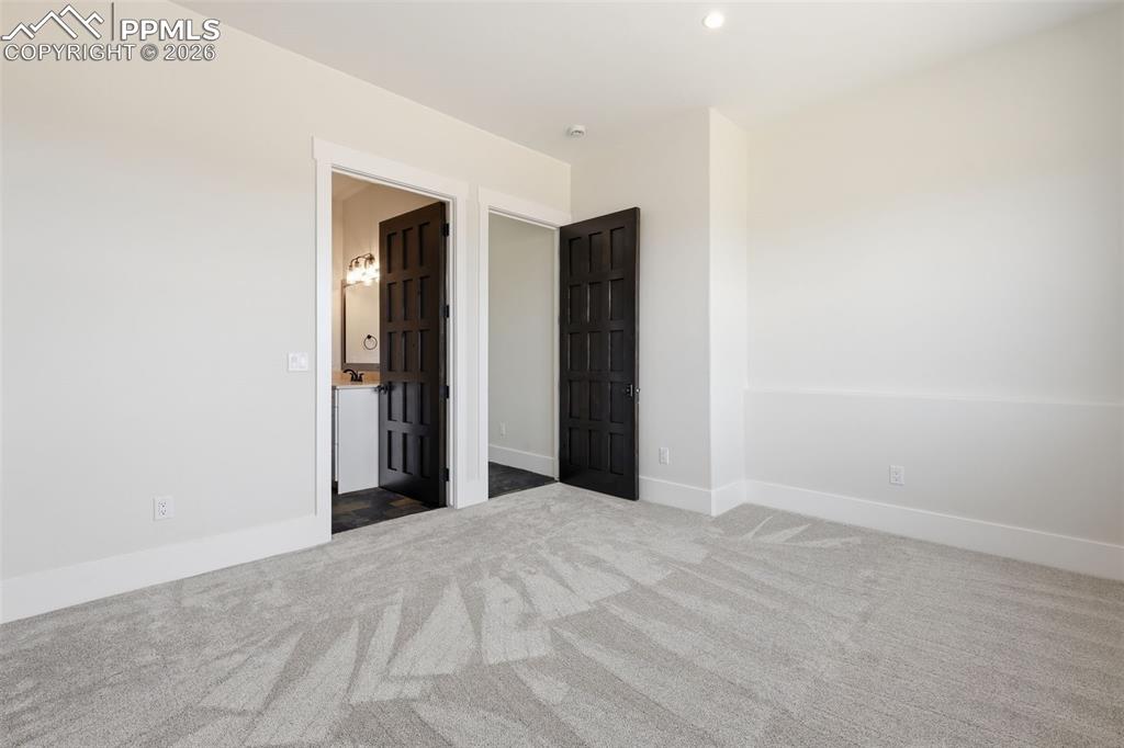 Image 37 of 45: 3rd bedroom on lower level looking into 3-piece bath and entrance hallway.