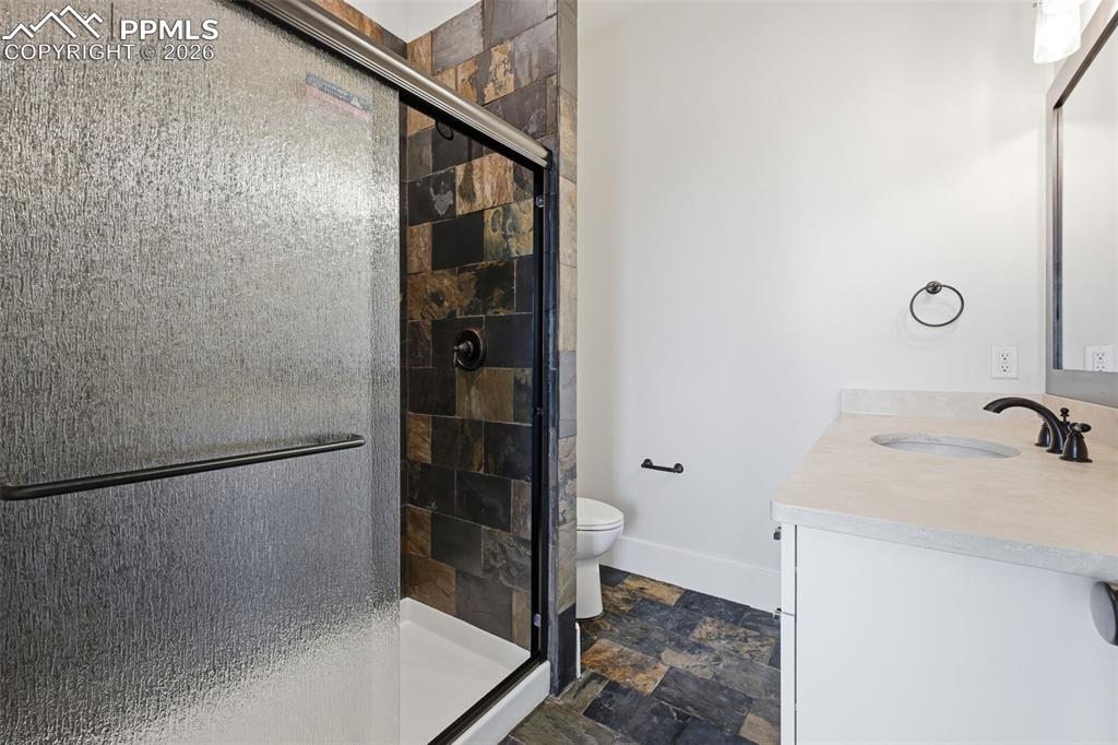 Image 38 of 45: Bathroom featuring stone finish flooring, vanity, and a shower stall