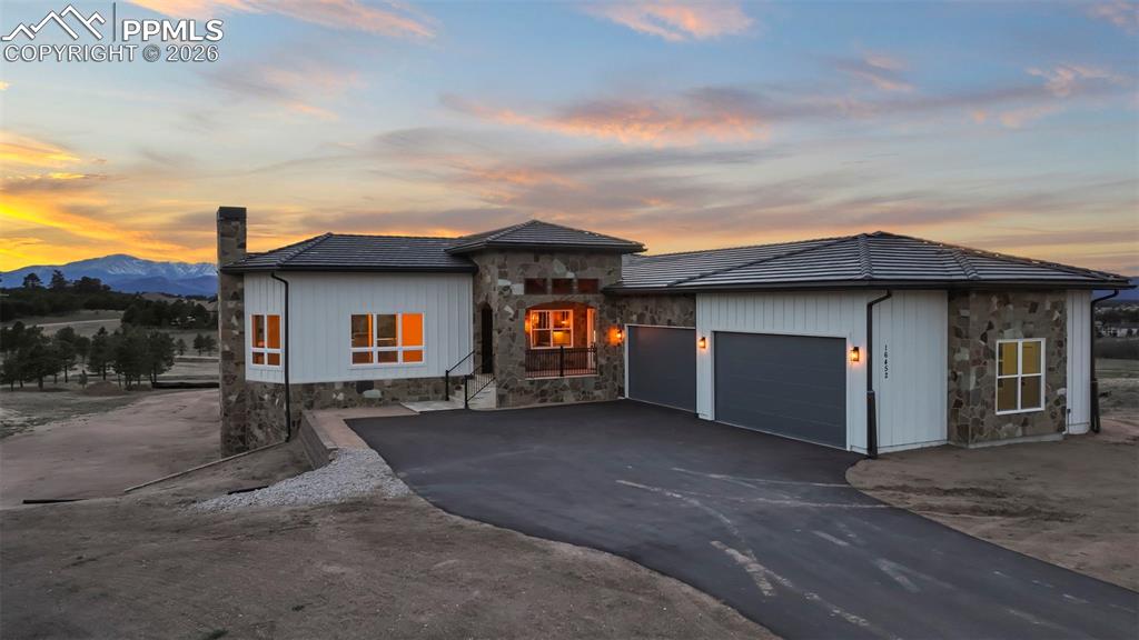 Image 4 of 45: View of front facade featuring stone siding, asphalt driveway, a garage, an