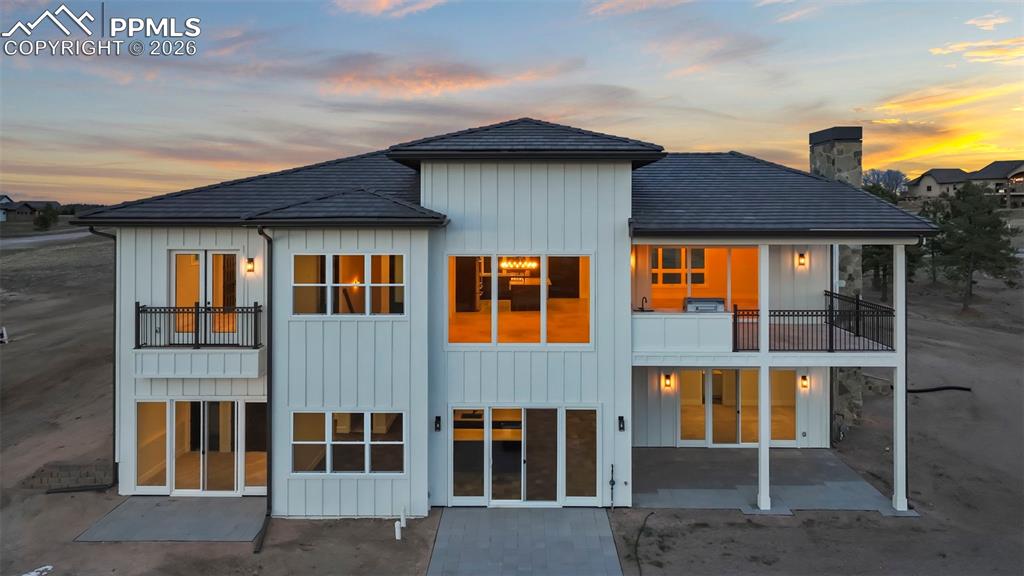 Image 45 of 45: Back of property featuring board and batten siding, a balcony, a patio, and