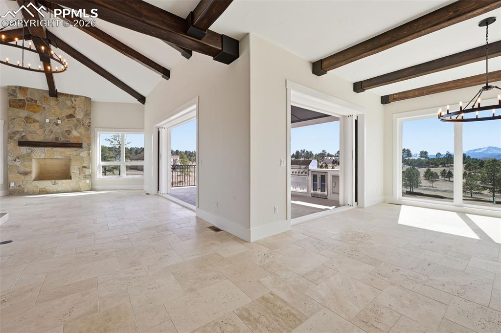 Image 9 of 45: Unfurnished living room with suspended lighting, stone tile flooring, beam 