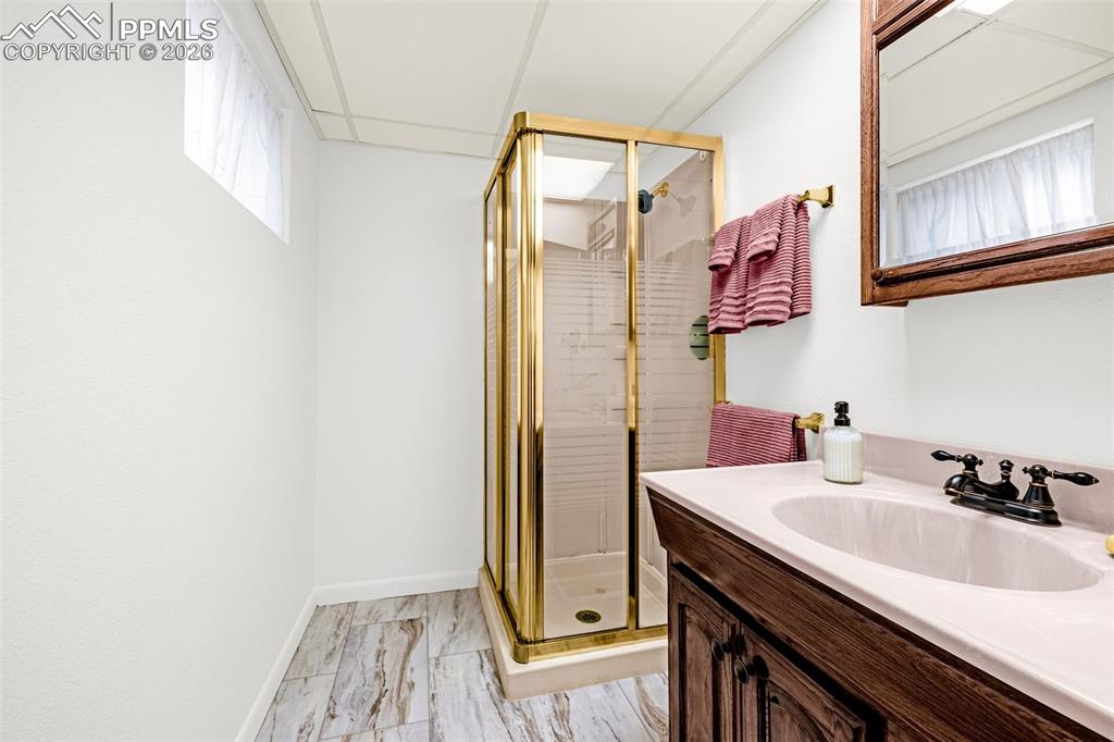 Image 26 of 44: The basement bathroom features a corner shower with a vanity and toilet