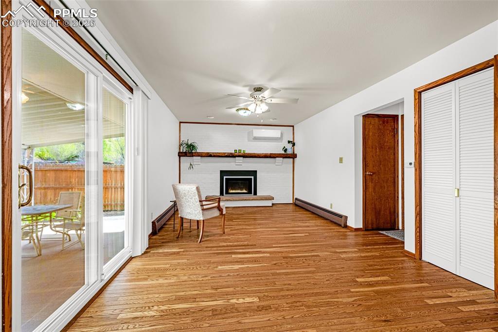 Image 3 of 44: The living space features hardwood floors, a white brick gas fireplace with