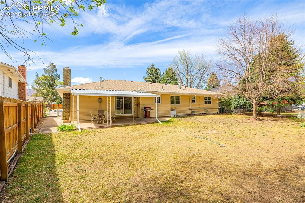 Image 31 of 44: The property features a spacious backyard with a lawn and a mature tree, al