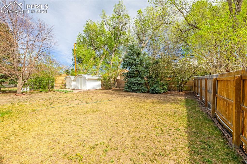 Image 32 of 44: The property features an extensive yard with two storage sheds, mature tree