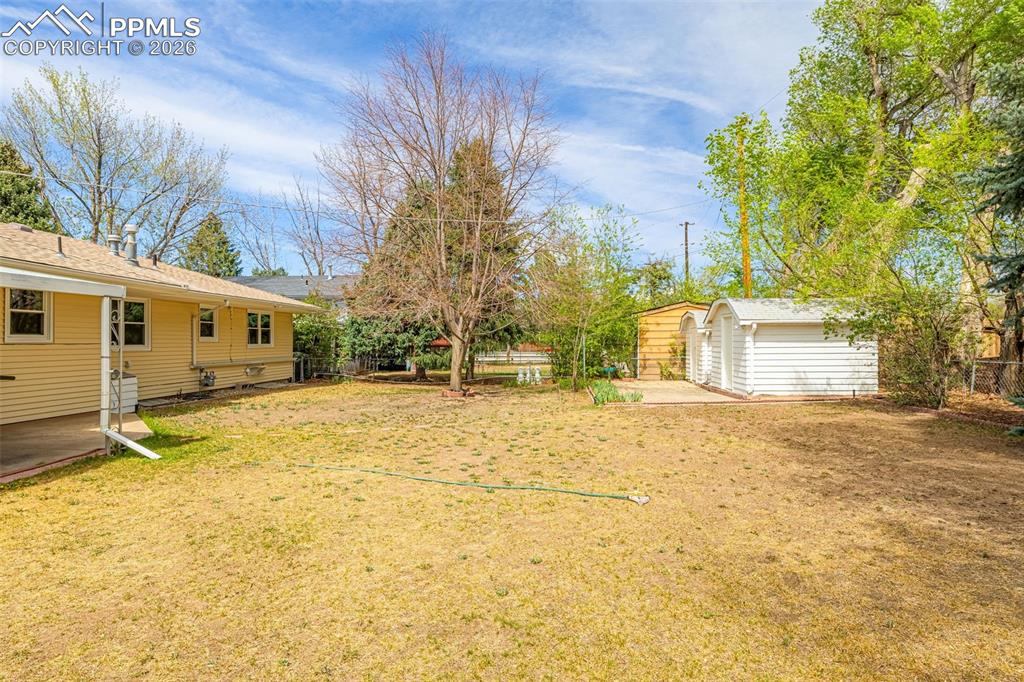 Image 33 of 44: The property features a spacious yard with a lawn, mature trees, and a conc