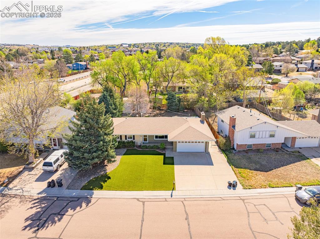 Image 37 of 44: The property features an artificial turf lawn, a paved driveway, and mature
