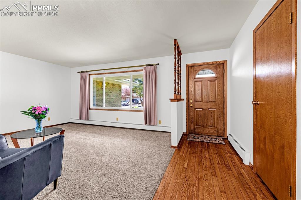 Image 6 of 44: Inviting entry area with hardwood floors, a wooden front door, and a carpet