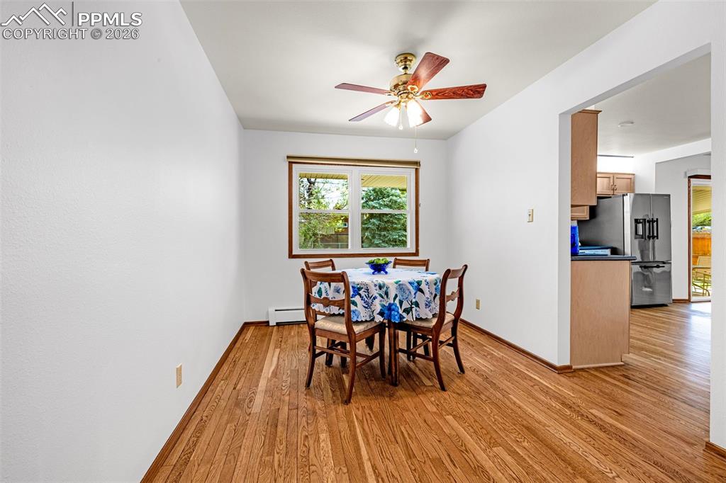 Image 8 of 44: Dining area next to the kitchen featuring wood flooring and a ceiling fan w