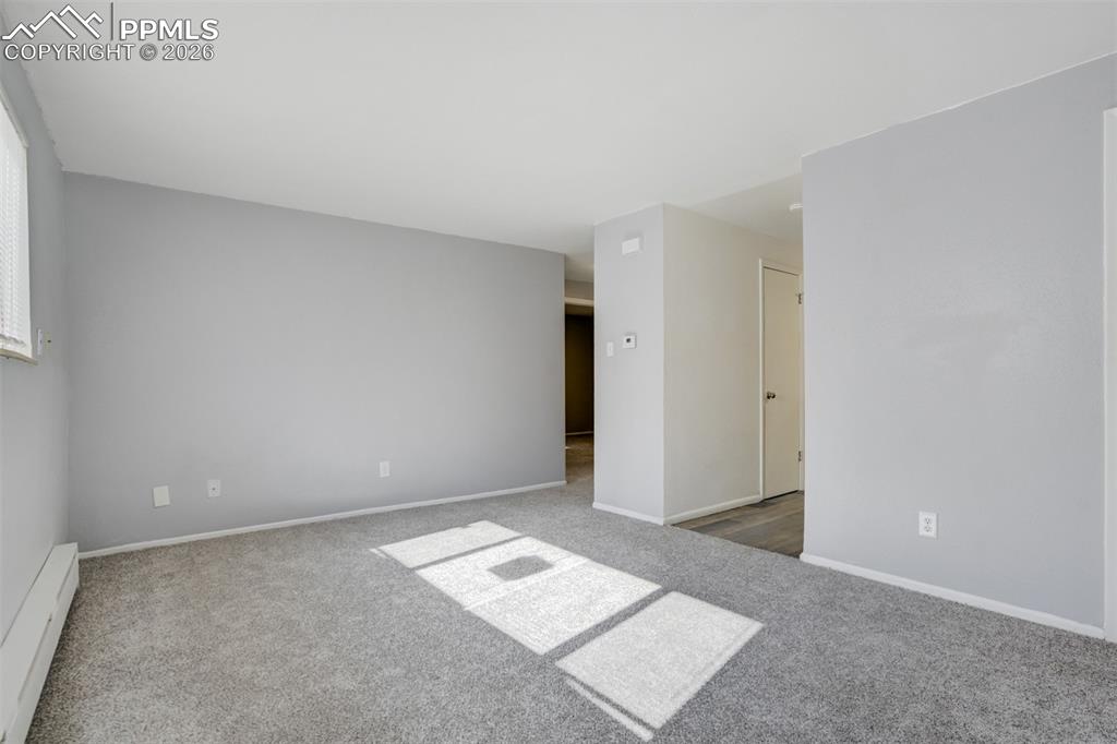 Image 11 of 42: Spare room featuring a baseboard heating unit and light carpet