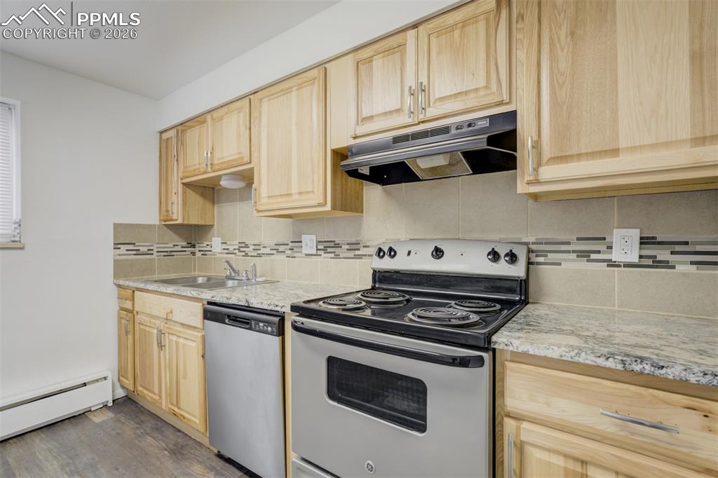 Image 17 of 42: Kitchen with light wood finish cabinetry, stainless steel appliances, dark 