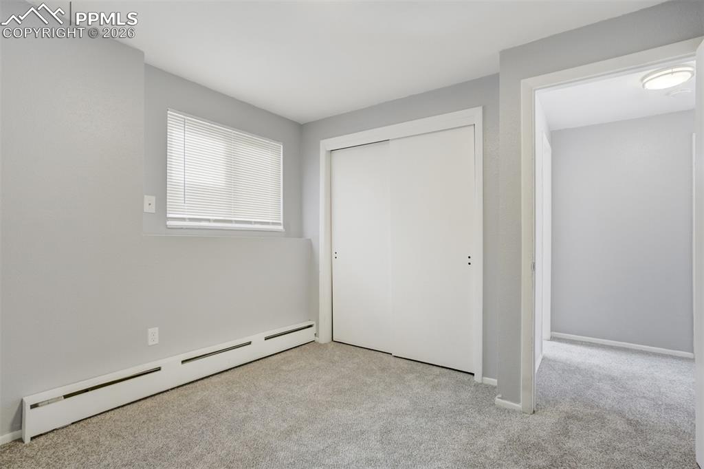 Image 19 of 42: Unfurnished bedroom with baseboard heating, light carpet, and a closet
