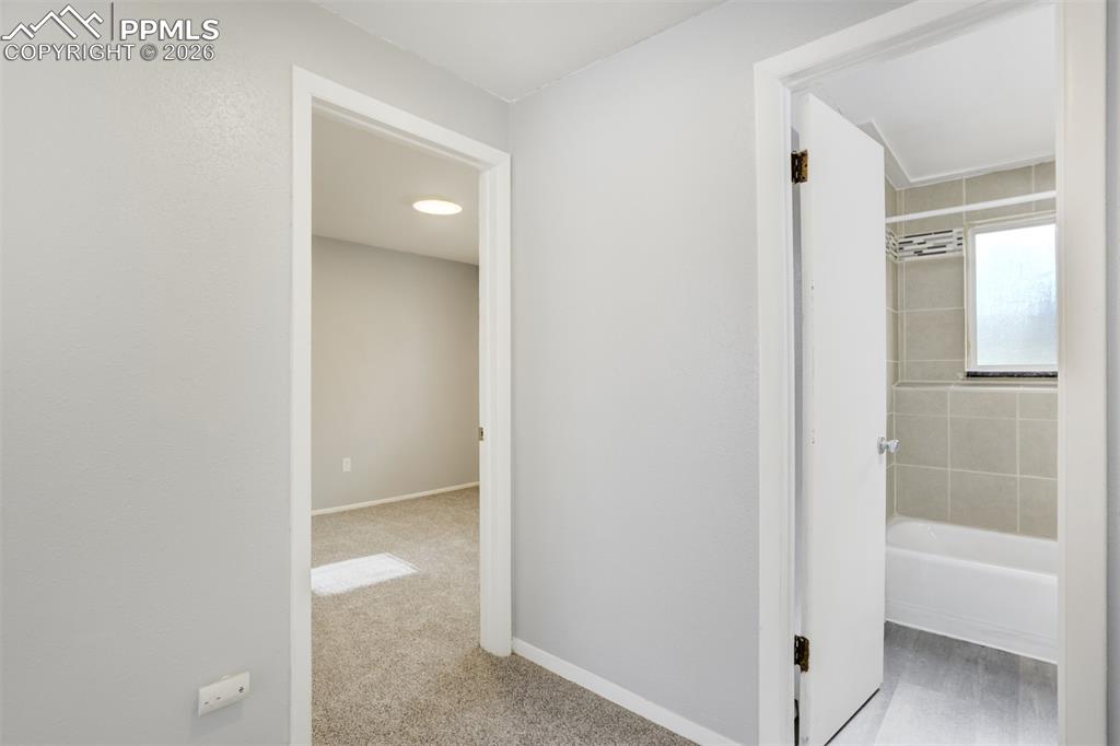 Image 23 of 42: Hallway featuring baseboards and light colored carpet